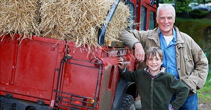 Grandfather and grandson standing next to truck of hay