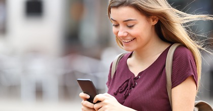 young woman smiling while looking at phone