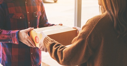 man in flannel shirt handing box to woman