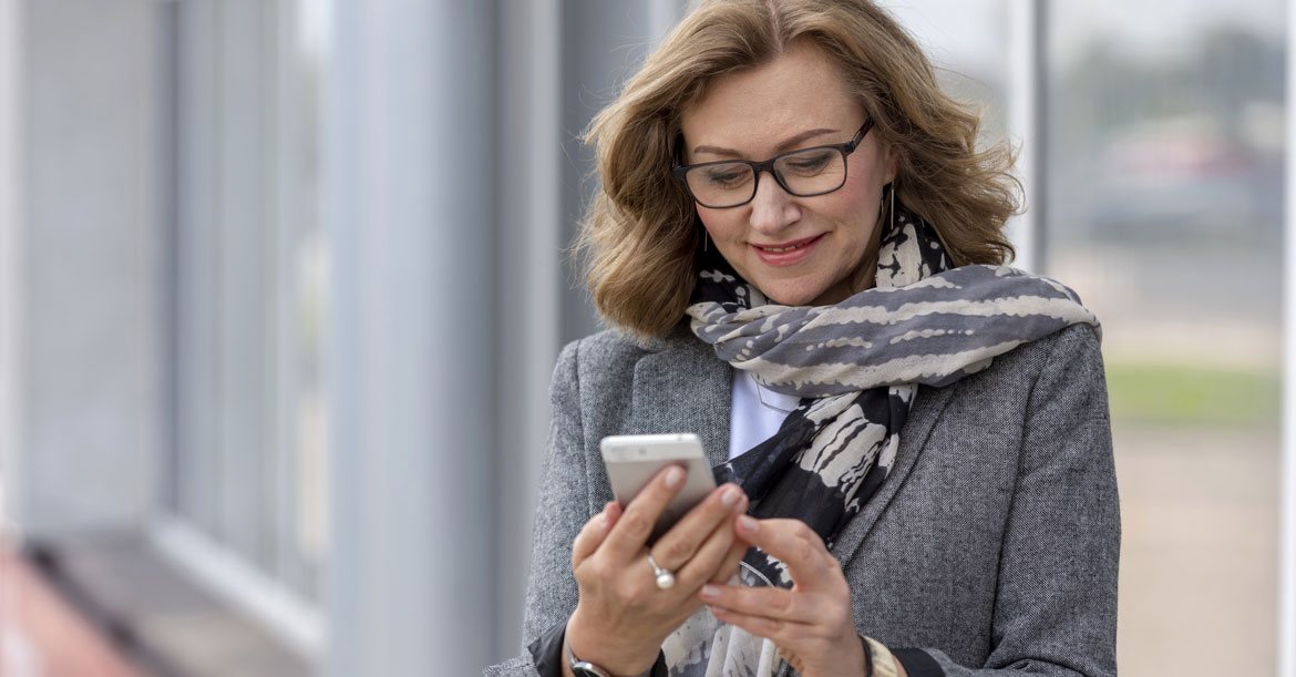 mature business woman wearing glasses looking at phone