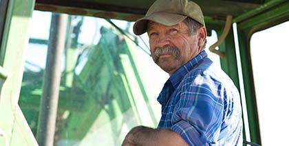 candid portrait of a senior male farmer sitting in a green tractor