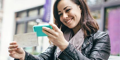 smiling young woman taking picture of check for mobile deposit