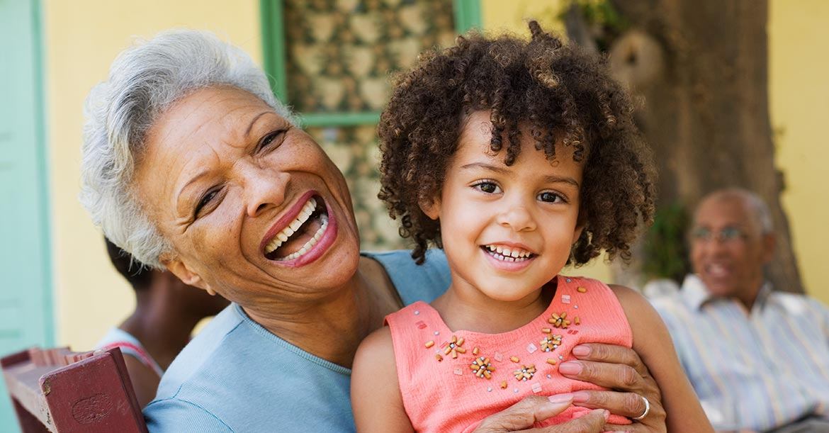 african american grandmother smiling while holding her granddaughter
