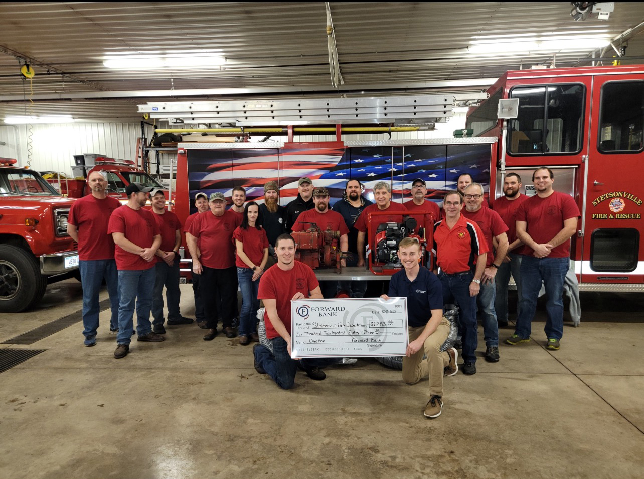 Taylor Shaw from Forward Bank presents the Stetsonville Fire Department with a donation for $6,200 to purchase a new portable water pump.