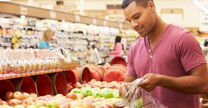 young man at grocery store placing apples in plastic bag