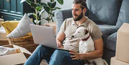 man with dog looking up credit score on laptop in house