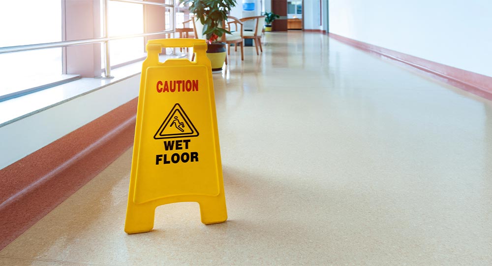 Wet floor sign in hallway, illustrating a common cause of business insurance claims such as slip-and-fall accidents.