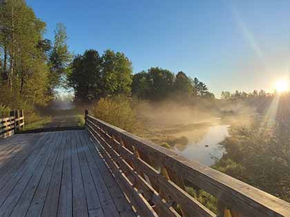wooden bridge over fogged covered water at sunset