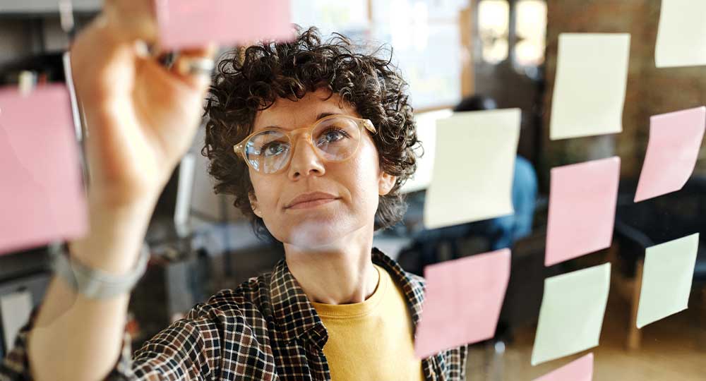 Business woman uses post it notes to compare employer retirement plans.