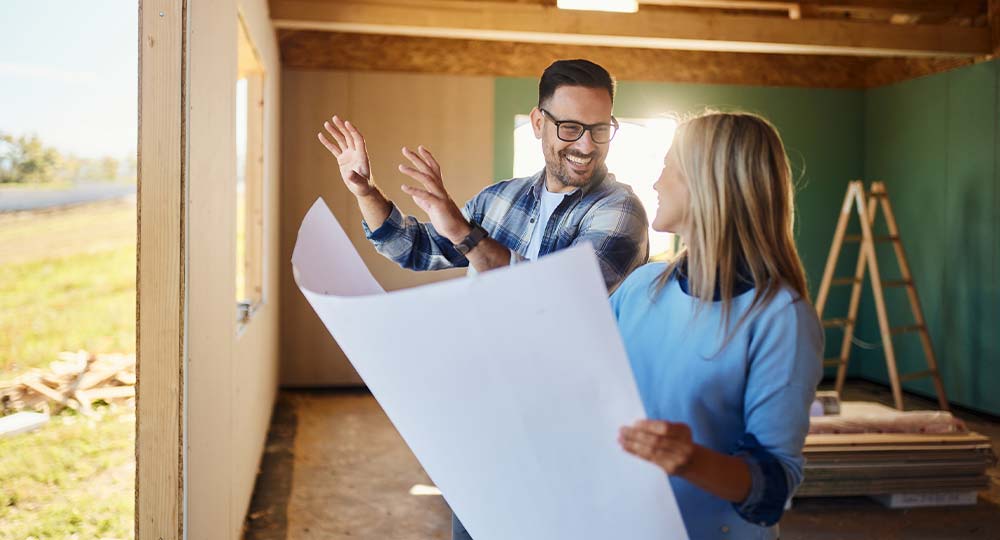 Couple reviewing home building plans during pre-construction planning phase.