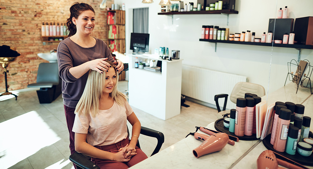 Small business salon owner working with a client, illustrating the importance of business insurance coverage.