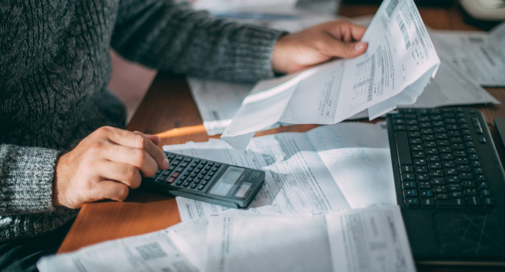 Small business owner reviewing invoices and payment documents at a desk, illustrating invoice verification and fraud prevention.