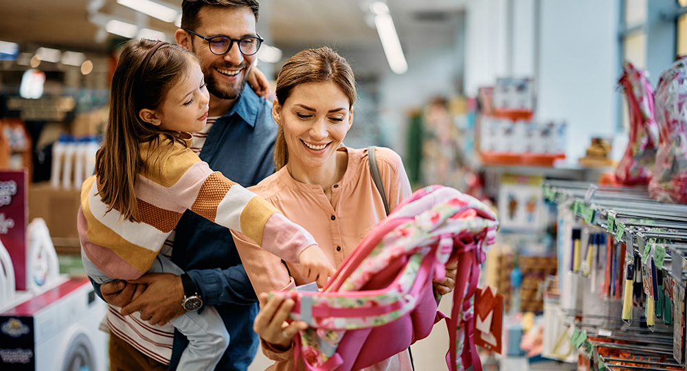 School shopping for elementary student with parents looking at a pink backpack