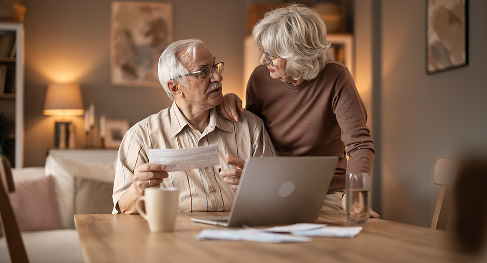 Senior couple reviewing Medicare documents together at home while preparing for Medicare Open Enrollment.